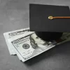 Graduation hat and dollar banknotes on table. Tuition fees concept