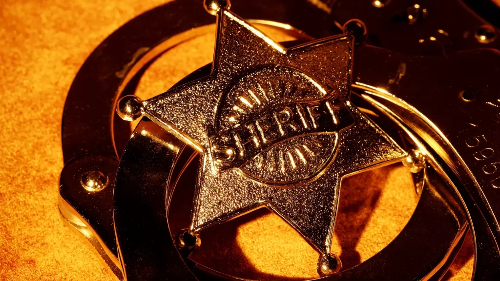 A sheriff's badge on a background of handcuffs.
