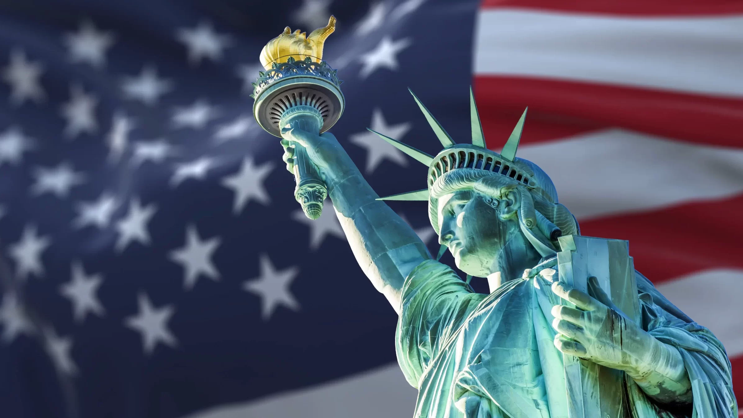 the statue of liberty with the blurry american flag waving in the background