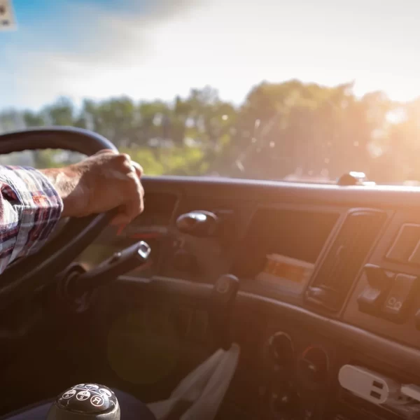 Truck driver keeps driving with one hands and change gears,The man Behind Semi Truck Steering Wheel,spot focus.