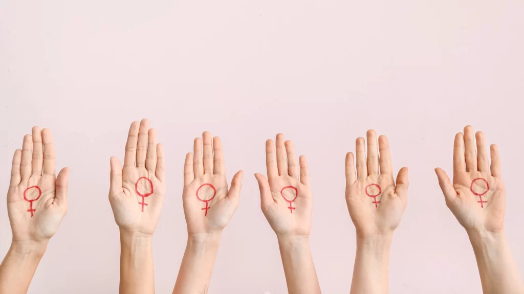 Women with drawn symbols of woman on their palms against color background. Concept of feminism