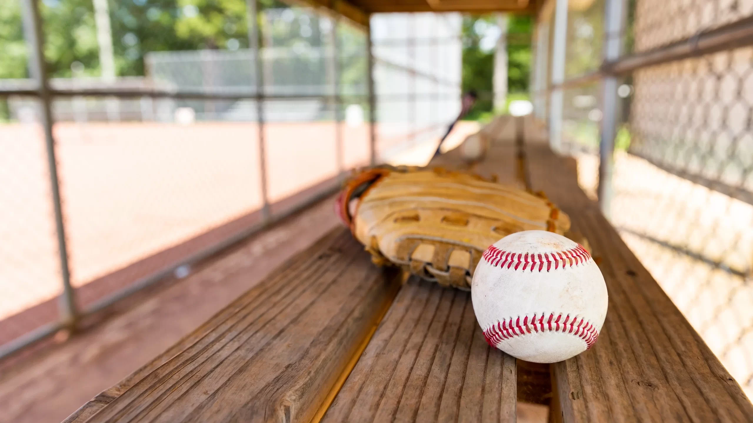 Baseball with glove on dugout bench with blurred background
