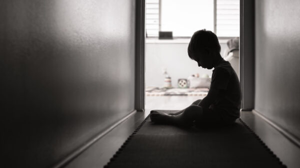 A boy looking down in a dark room.
